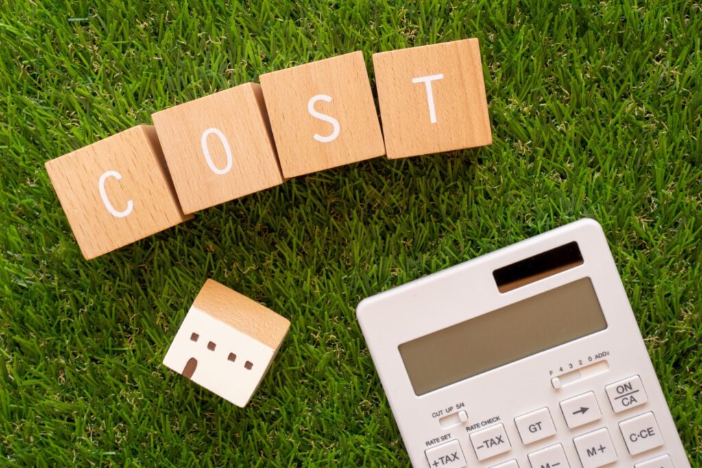 コスト | 「COST」と書かれた積み木ブロックと家のおもちゃと電卓